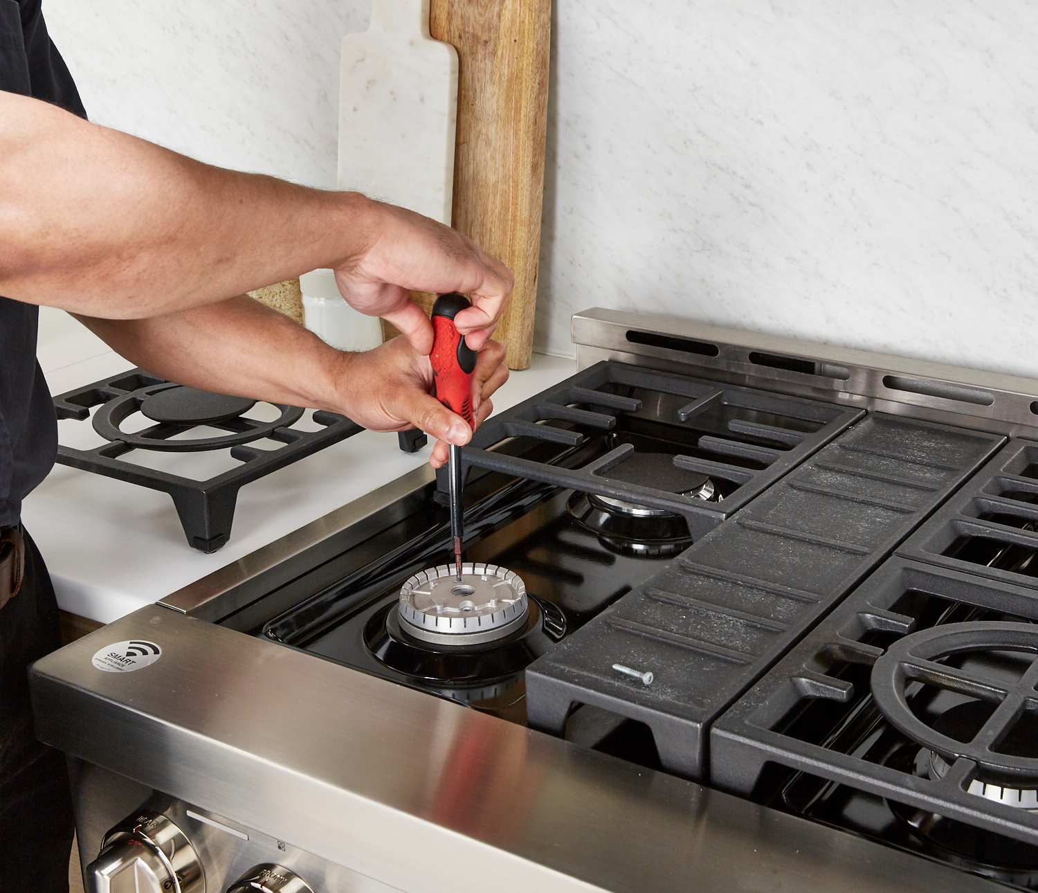 Technician repairing gas stove ignition system with precision tools