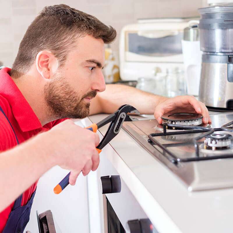 Professional gas stove repair technician working on burner maintenance